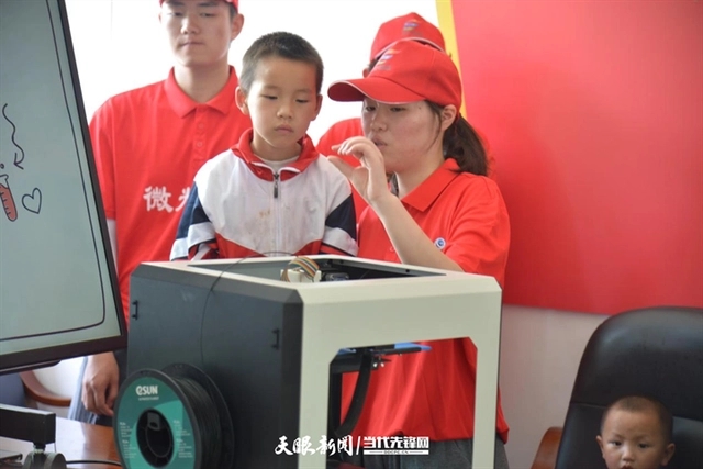 志愿者带领学生参观3D打印机.webp.jpg